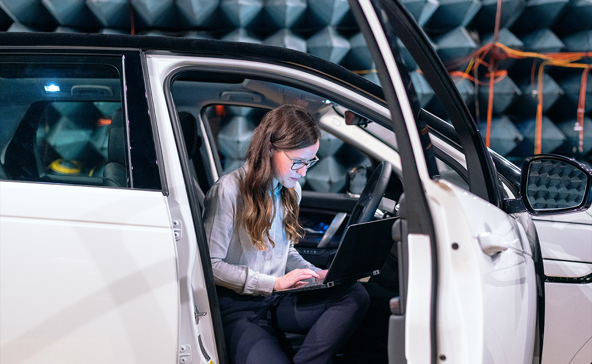 Engineer checking data on a laptop inside a car